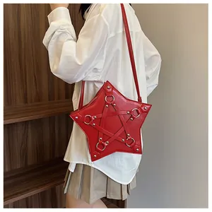 Close-up of a stylish red star-shaped bag with rivet details being worn by a model