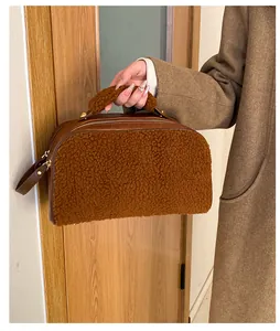 Close-up of brown faux shearling cosmetic bag held by hand featuring plush texture