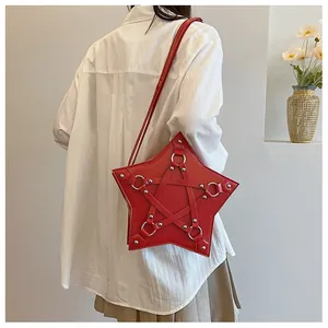 Stylish red star-shaped shoulder bag with silver studs worn by model in casual setting
