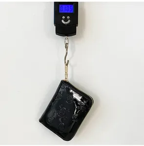 Balance numérique pesant un portefeuille en cuir verni noir gaufré d'un crâne