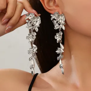 Detailed view of fashionable silver metallic flower long dangle earrings worn by a model
