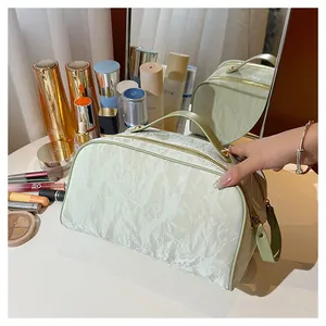 Large capacity pale green cosmetic bag with crinkle texture and gold double zippers.