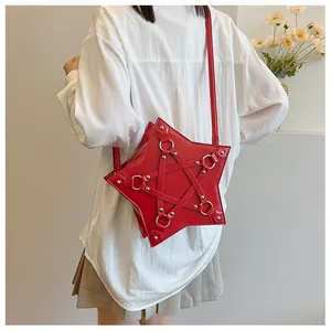 Red star-shaped crossbody bag with metal ring decorations worn on a simple white shirt