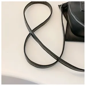Detail view of a black star-shaped crossbody bag featuring a slim shoulder strap.