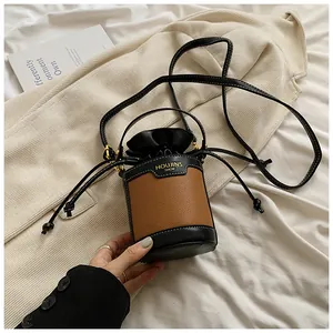Close-up detail of a minimalist color-blocked cylindrical bucket bag with drawstring