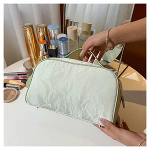 Close-up of a pale green cosmetic bag with crinkled texture shown on a makeup vanity table