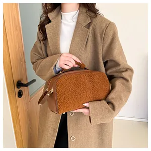 Model holding a brown faux fur plush cosmetic bag with a large capacity design.