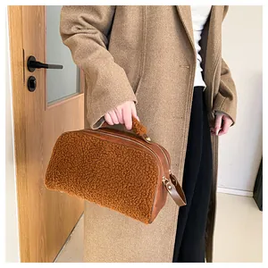 Close-up view of a stylish brown fuzzy makeup bag held by a person in a classic autumn coat