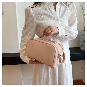 Close-up detail of a large pink floral textured cosmetic bag held by a model in white.