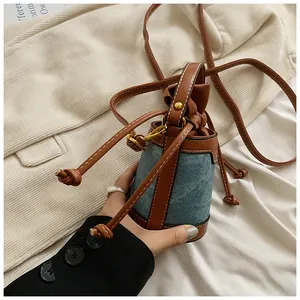 Close-up of a women's denim patchwork bucket bag with drawstring closure and leather strap.