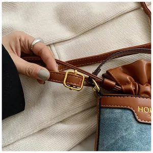 Close-up of the denim and brown leather patchwork bucket bag with a golden buckle detail