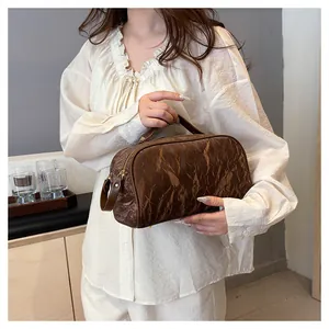 Close-up of a brown marble textured cosmetic bag held by a model in a casual setting
