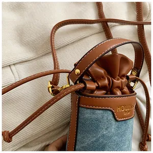 Close-up of denim and leather patchwork bucket bag with golden drawstring closure