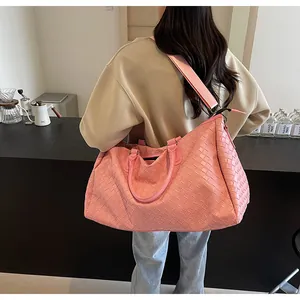 Detailed view of pink woven travel bag worn by model in lifestyle setting