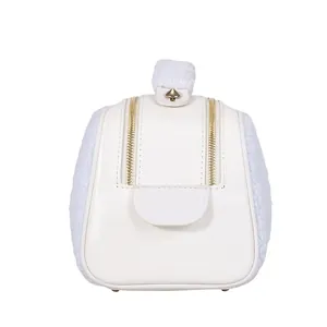 Close-up of stylish white fuzzy cosmetic bag featuring leather panel and dual golden zippers