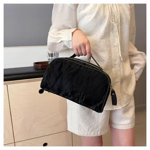 Large capacity portable black crinkle texture cosmetic bag shown held by a model in detail