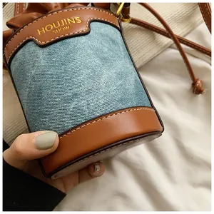 Close-up detail of denim and leather spliced bucket bag with drawstring