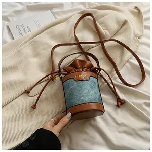 Denim and leather patchwork bucket bag with drawstring closure and top handle