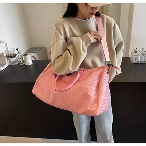Pink woven duffle bag for travel and fitness, shown being worn by a model in a lifestyle setting.