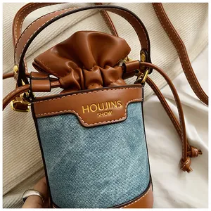 Close-up detail of a minimalist denim and leather bucket bag with drawstring top