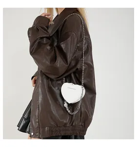 Close-up of a white heart-shaped mini crossbody bag with elegant beaded and metal chains
