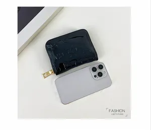 Portefeuille noir brillant à tête de mort à côté d'un smartphone pour comparer la taille.