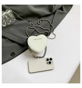 Detailed view of white heart-shaped mini crossbody bag with smartphone for size comparison