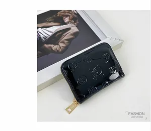 Gros plan d'un portefeuille en cuir verni noir avec motif tête de mort et zip doré