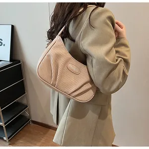 Detailed view of a stylish beige pleated cloud shoulder bag worn with an elegant blazer.