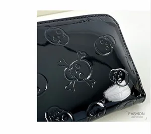 Détail rapproché d'un portefeuille en cuir verni noir brillant à motifs de crânes