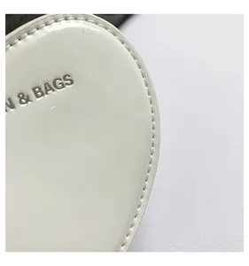 Close-up detail of white glossy heart handbag with silver N & BAGS lettering