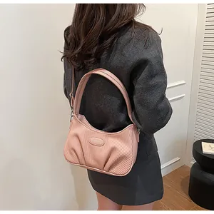 Back view of a woman carrying a pink pleated cloud shoulder bag with minimalist design
