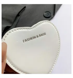 Close-up detail of white heart-shaped mini lipstick purse with stamped fashion text