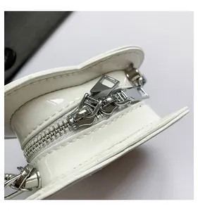 Detailed close-up of metal zipper on white heart-shaped patent leather mini bag