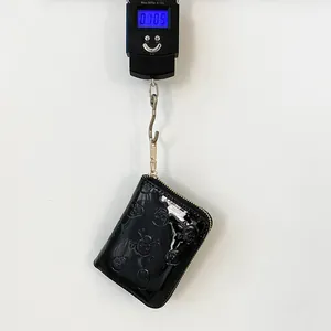 Détail d'un petit portefeuille noir brillant avec gaufrage de crâne pesant 0,385 kg