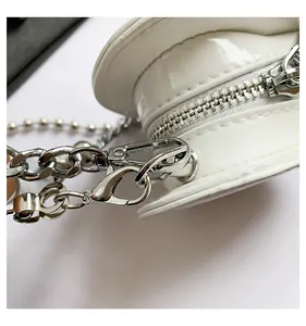 Close-up of white heart bag showing patent leather texture and silver chain hardware details