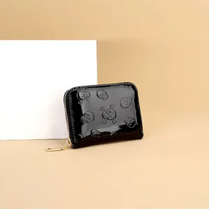 Gros plan d'un petit portefeuille noir brillant à motifs tête de mort embossés et zip
