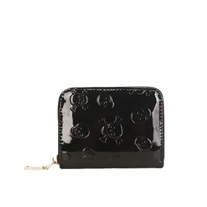 Détail du porte-monnaie en cuir verni noir avec motif tête de mort et os gaufré.