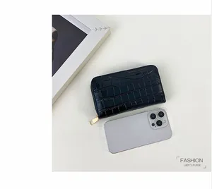 Damenbrieftasche mit Krokodilmuster neben einem Smartphone zum Größenvergleich