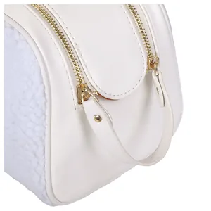 Close-up of a white shearling and leather cosmetic bag with gold zippers and handle