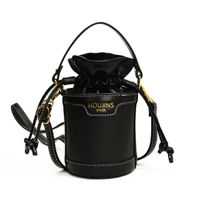 Front view of black leather cylinder bucket bag with drawstring closure and gold hardware