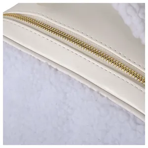 Close-up of golden zipper and white plush texture on a stylish cream makeup bag