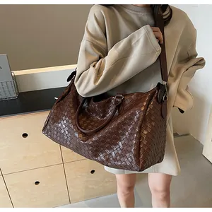 Detailed view of a fashionable brown woven travel bag for women worn on the shoulder