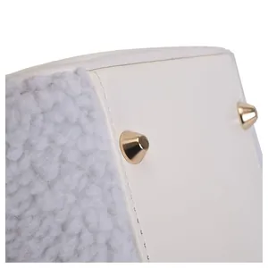 Detail shot of white faux leather and grey sherpa cosmetic bag with gold metal studs.