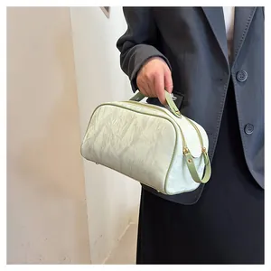Detail view of a portable large capacity cosmetic bag with wrinkled texture and green handle