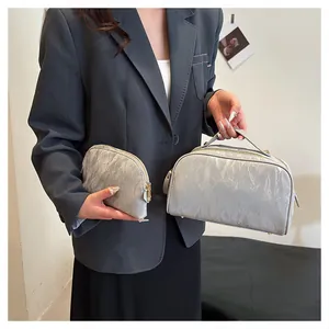An Asian model holding two silver textured cosmetic bags in medium and small sizes