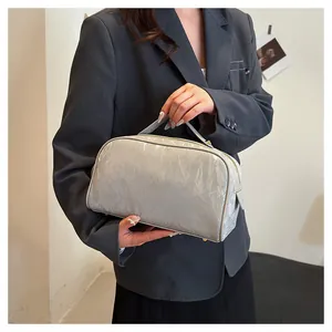 Large capacity silver crinkled texture travel cosmetic bag held by a model in detail view