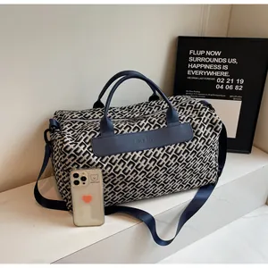 Vue détaillée du motif géométrique et du patch en cuir sur ce grand sac de voyage bleu.