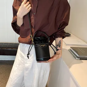 Minimalist chic black cylinder bucket bag with drawstring closure and shoulder strap