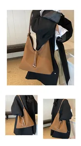 Detailed view of the large brown minimalist tote bag worn by a model in black outfit